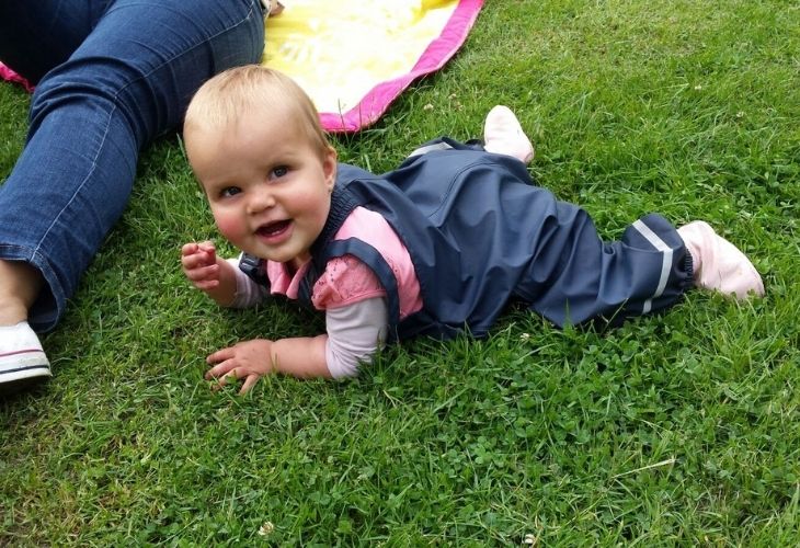 Baby in regenbroek in het gras baby camping tips