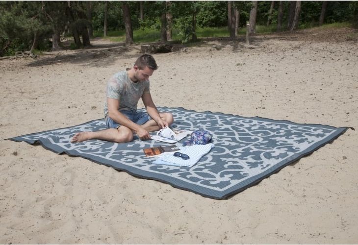 Bo camp chillmat op zand, meneer is aan het lezen 