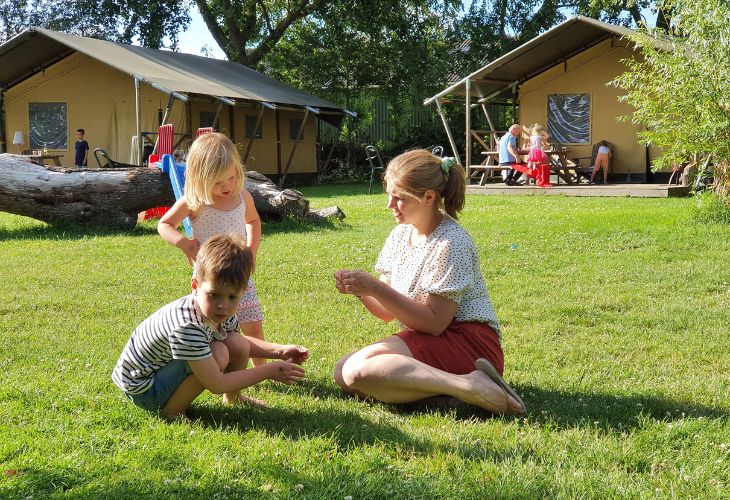 Glamping bij de boer moeder met twee kinderen op gras voor glampingtenten
